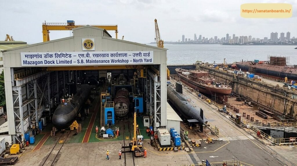 माझगांव डॉक लिमिटेड – एस.बी. रखरखाव कार्यशाला – उत्तरी यार्ड An aerial view of the Mazagon Dock Limited S.B. Maintenance Workshop - North Yard showing submarine hulls inside covered bays and docked naval vessels alongside dry dock facilities with the Mumbai skyline across the water.