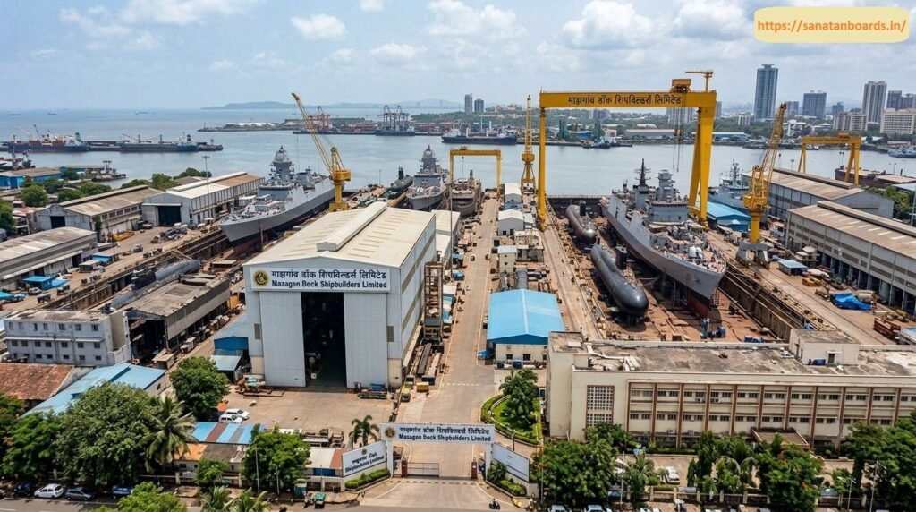 माझगांव डॉक शिपबिल्डर्स लिमिटेड An aerial panorama of the Mazagon Dock Shipbuilders Limited complex in Mumbai, displaying naval destroyers, stealth frigates, submarines in dry docks, giant Goliath gantry cranes, assembly workshops, and the surrounding ocean port cityscape.